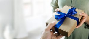 hand giving gift box with blue ribbon to a woman. copy space